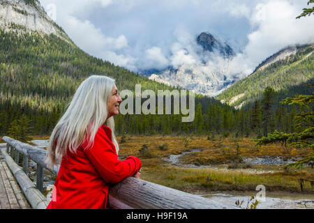 La donna caucasica appoggiata sulla ringhiera in legno ammirando la montagna Foto Stock