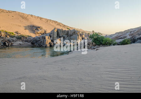 Il fiume Kunene nella parte anteriore del torreggiante antica Namib Desert dune di sabbia di Namibia e Angola Foto Stock