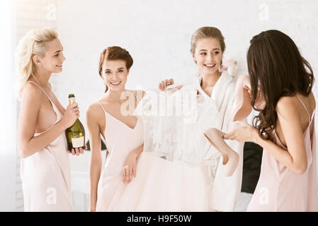 Allegro bridesmaids aiutando la sposa per ottenere pronto per matrimoni Foto Stock