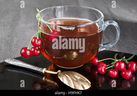 Tè con ciliegie in un bicchiere di vetro. Foto Stock