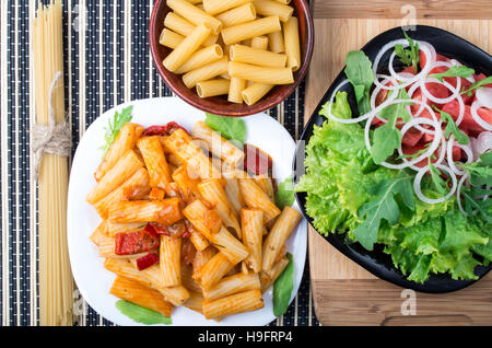 Vista superiore del cotto rigatoni pasta con salsa di verdure e un piatto di verdura fresca insalata Foto Stock