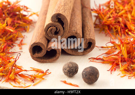 Bastoncini di cannella, aromatici zafferano e peperoni gialli sul vassoio in legno close-up con profondità di messa a fuoco. Foto Stock