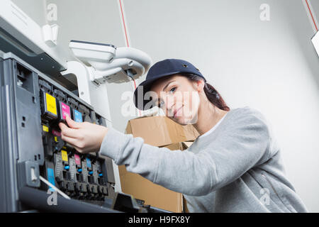 Donna che fissa la cartuccia nella stampante in ufficio Foto Stock