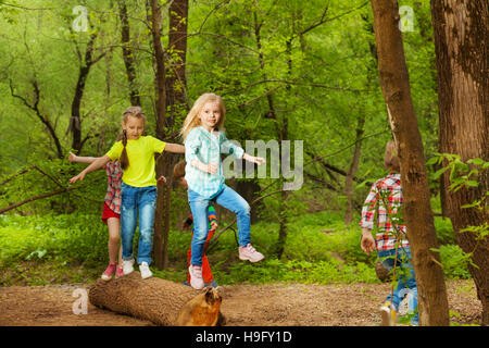 Contenti i bambini permanente di bilanciamento sul log in foresta Foto Stock