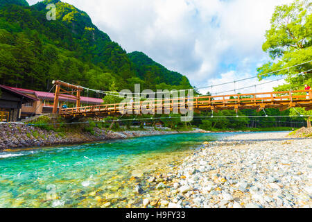 I turisti giapponesi si cammina su Kappa-Bashi Bridge visto dal basso angolo accanto a rocce di Azusa-gawa River in Kamikochi Foto Stock