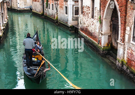 Gondoliere la propulsione di una gondola (veneziana tradizionale barca) attraverso i favolosi piccoli canali di Venezia. Foto Stock