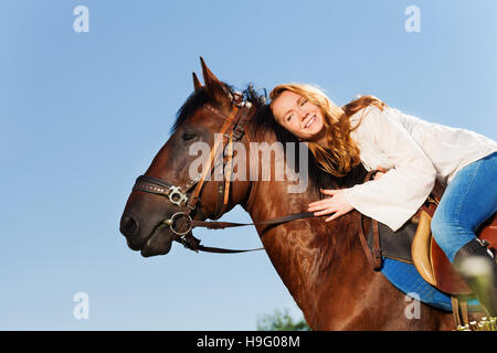 Donna sorridente che abbraccia la splendida baia cavallo Foto Stock