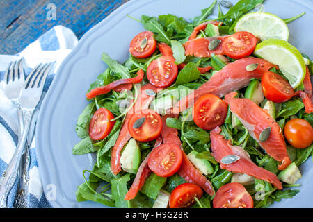 Salmone salato con erbe aromatiche, pomodori e insalata su una tavola di legno. Amore per un sano cibo crudo concetto Foto Stock