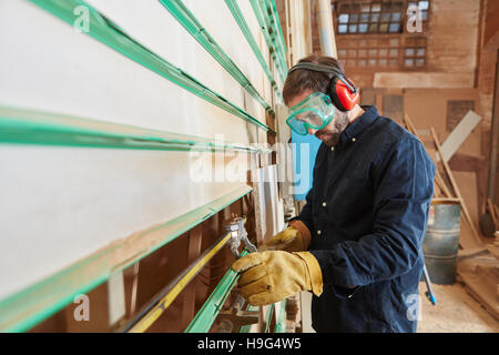 Carpenter Taglia legno con pannello verticale visto nella bottega del falegname Foto Stock