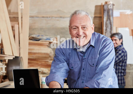 Sorridente senior citizen come carpentiere in falegnameria shop Foto Stock