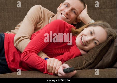 Giovane sdraiato su un lettino di guardare la TV Foto Stock