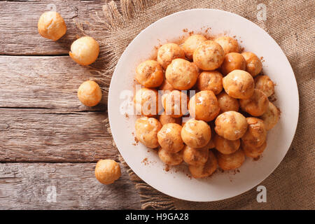 Loukoumades ciambelle con miele e cannella close-up su una piastra. Vista orizzontale dal di sopra Foto Stock