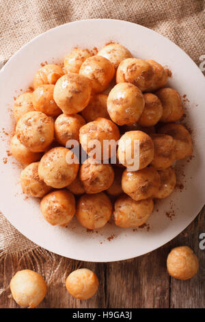 Loukoumades greco ciambelle con miele e cannella close-up su una piastra. vista verticale da sopra Foto Stock