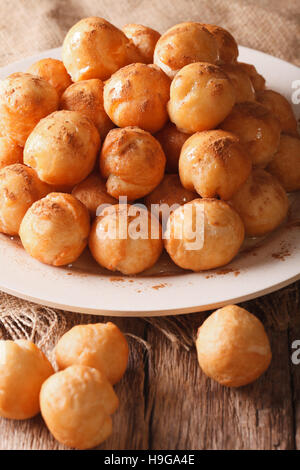 In casa ciambelle fritte loukoumades con miele e cannella close-up su una piastra verticale. Foto Stock