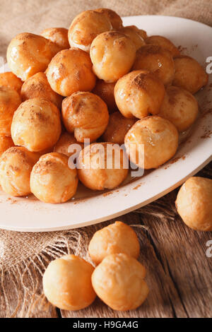 Loukoumades greco ciambelle con miele e cannella close-up su una piastra verticale. Foto Stock