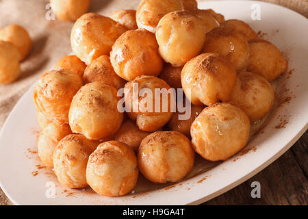 Loukoumades ciambelle con miele e cannella close-up su una piastra. Posizione orizzontale Foto Stock