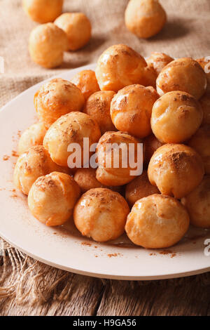 Loukoumades ciambelle con miele e cannella close-up su una piastra verticale. Foto Stock