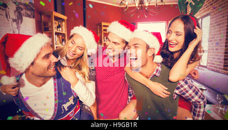 Immagine composita di uomini che indossano il natale indossando dando alle donne piggyback rides Foto Stock