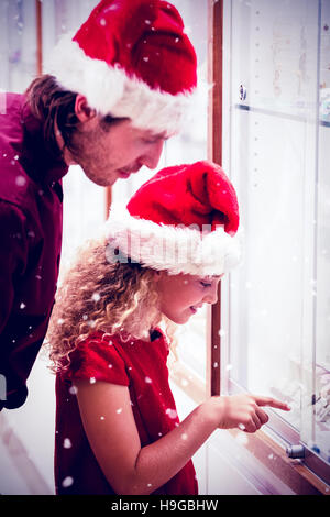 Immagine composita della vista laterale del padre e figlia in abito di natale guardando il display di gioielli Foto Stock