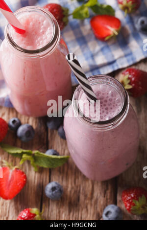 Smoothie con fragole e mirtilli in bottiglie da vicino sul tavolo. vista verticale da sopra Foto Stock