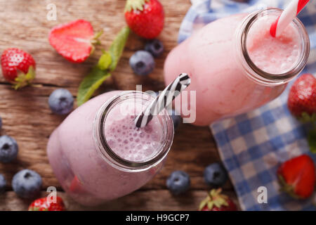Smoothie con fragole e mirtilli in bottiglie da vicino sul tavolo. vista orizzontale dal di sopra Foto Stock