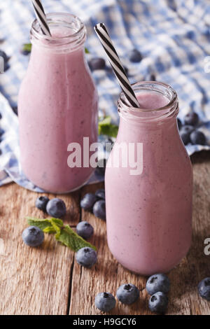 Freddo frullato di mirtilli con la menta in bottiglie di vetro vicino sul piano verticale. Foto Stock