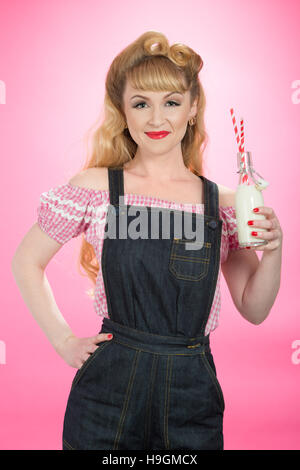 Pin Up girl bere latte da un retrò swing top bottiglia con cannucce Foto Stock