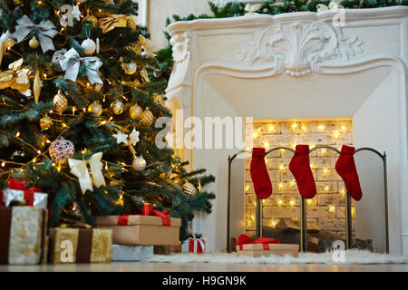 Decorate albero di natale, stack di dono-box e camino con calzini rossi preparato per la notte di Natale Foto Stock