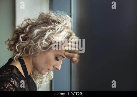 Sconvolto imprenditrice appoggiata sulla finestra Foto Stock