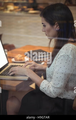 Imprenditrice utilizzando laptop in cafÃ© Foto Stock