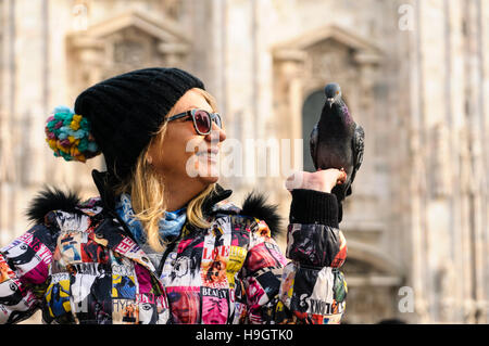 Una donna che tiene fuori il cibo per i piccioni in Piazza del Duomo, Milano, Italia Foto Stock