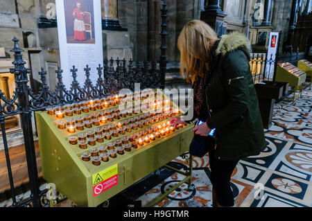 Una donna accende una candela per ricordare un membro della famiglia per il Duomo di Milano (Duomo di Milano), Italia. Foto Stock