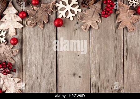 Rustico angolo di Natale confine con ornamenti in legno e bacche su un vecchio Sfondo legno Foto Stock