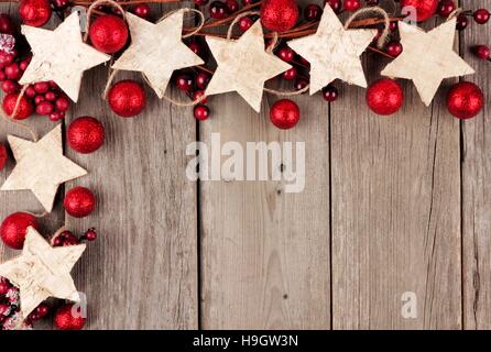 Rustico angolo di Natale confine con la stella di legno ornamenti e baubles su un vecchio Sfondo legno Foto Stock