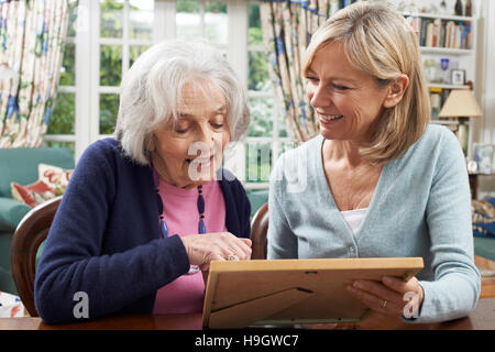 Senior donna Guarda la foto nella cornice con femmina matura il prossimo Foto Stock