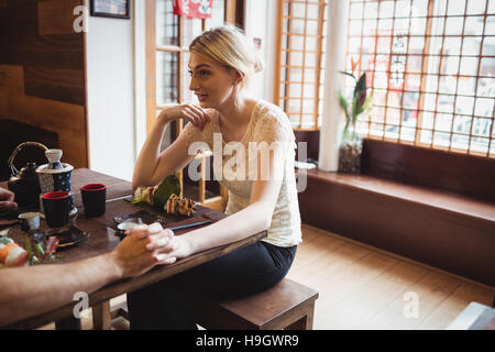 Giovane romancing pur avendo il sushi al ristorante Foto Stock