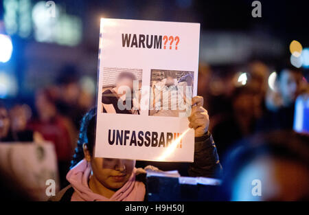 Hameln, Germania. 23 Nov, 2016. Un membro della famiglia della vittima che tiene un cartello con la dicitura 'Perché?' e 'incredibile!" accanto alla foto della vittima nella solenne veglia nella Prinzen Street in Hameln, Germania, 23 novembre 2016. Un uomo legato ad una giovane donna alla sua auto e trascinato il suo per 250 metri di domenica scorsa. (Attenzione i redattori: le immagini della vittima sono pixelized per ragioni giuridiche in materia di diritti personali.) Foto: Julian Stratenschulte/dpa/Alamy Live News Foto Stock