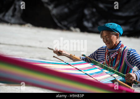 (161124) -- DULONGJIANG, nov. 24, 2016 (Xinhua) -- Il 73-anno-vecchio Li Wenshi tesse un tappeto in Dizhengdang villaggio di Dulongjiang Township, a sud-ovest della Cina di Provincia di Yunnan, nov. 23, 2016. Dulongjiang Township è casa per persone di Dulong gruppo etnico. A causa di abominevoli condizioni naturali, l'economia locale è stato sviluppato in passato. Dopo anni di sviluppo, le strade sono state lastricate e moderne case di abitazione costruita per sostituire la sterpaglia-case coperte. Il rurale assicurazione medica ha coperto il 98 percento degli abitanti del villaggio e tutti i bambini in età scolare hanno ricevuto l'educazione a scuola. L'orecchio medio Foto Stock