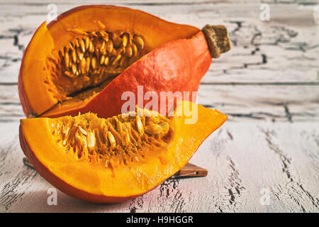 Red kuri squash (Hokkaido zucca) su bianco rustico sfondo di legno Foto Stock