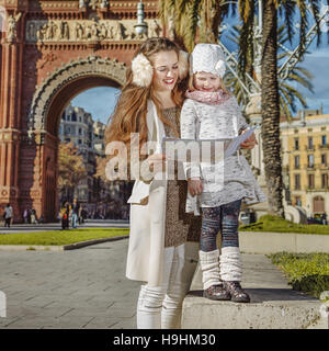 A Barcellona per una perfetta inverno. Felice giovane madre e bambino vicino al Arc de Triomf a Barcellona Spagna guardando la mappa Foto Stock