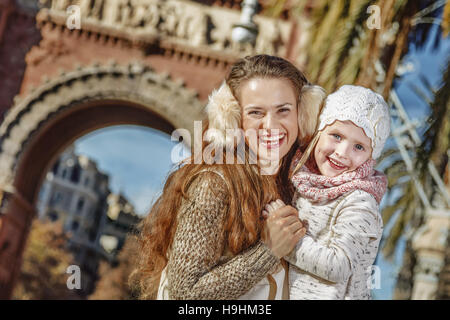 A Barcellona per una perfetta inverno. Ritratto di sorridere alla moda di madre e bambino vicino al Arc de Triomf a Barcellona Spagna avvolgente Foto Stock