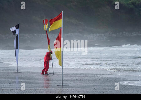 Un bagnino RNLI colloca un flag di sicurezza su Fistral Beach in Newquay, Cornwall. Foto Stock
