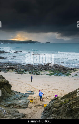 Tempesta Angus avvicinando poco Fistral come due persone si radunano le alghe sulla spiaggia. Newquay, Cornwall. Regno Unito meteo. Foto Stock