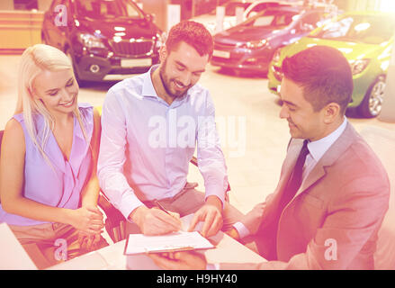 Coppia felice con il rivenditore di auto in auto show o salon Foto Stock