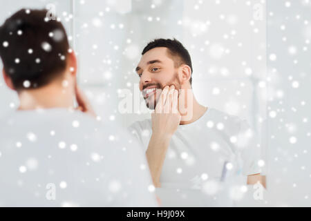 Felice giovane uomo di applicare la crema per il viso a bagno Foto Stock