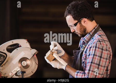 Professione, carpenteria, falegnameria concetto di persone - falegname con asse di legno e notebook controllare le sue note in officina Foto Stock