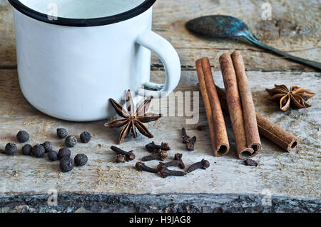 Ingredienti per la cottura Masala chai o vin brulé in bianco mug rustico con spezie su sfondo di legno per l'inverno e Natale. Alimentare la vita ancora Foto Stock