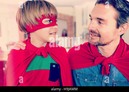 Padre e figlio fingendo di essere il supereroe in salotto Foto Stock