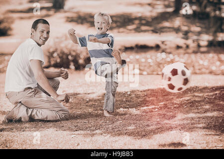 Padre giocando a calcio con suo figlio durante l'estate Foto Stock