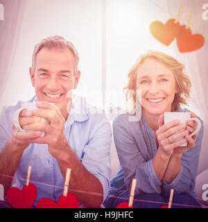 Immagine composita di sorridere coppia di mezza età seduta sul divano di caffè Foto Stock